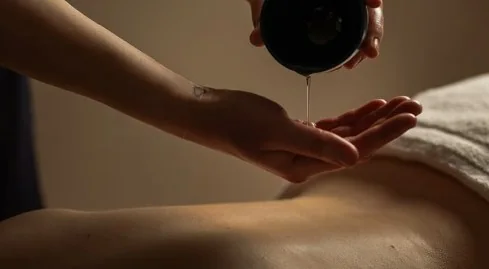 Massage oil poured into a therapist's hand